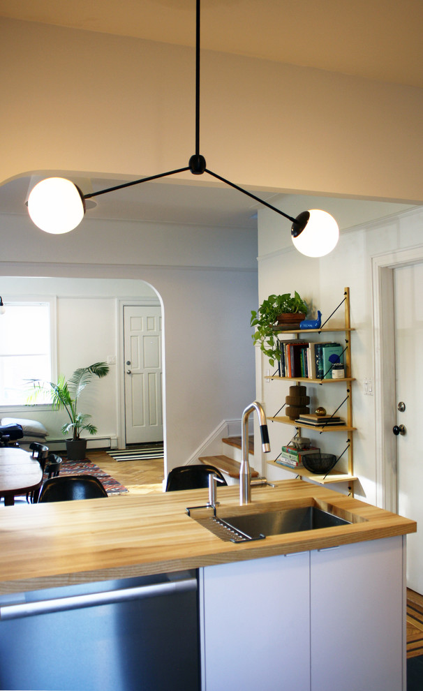 Foto di una cucina minimalista di medie dimensioni con lavello sottopiano, ante lisce, ante bianche, top in legno, elettrodomestici in acciaio inossidabile e pavimento in vinile