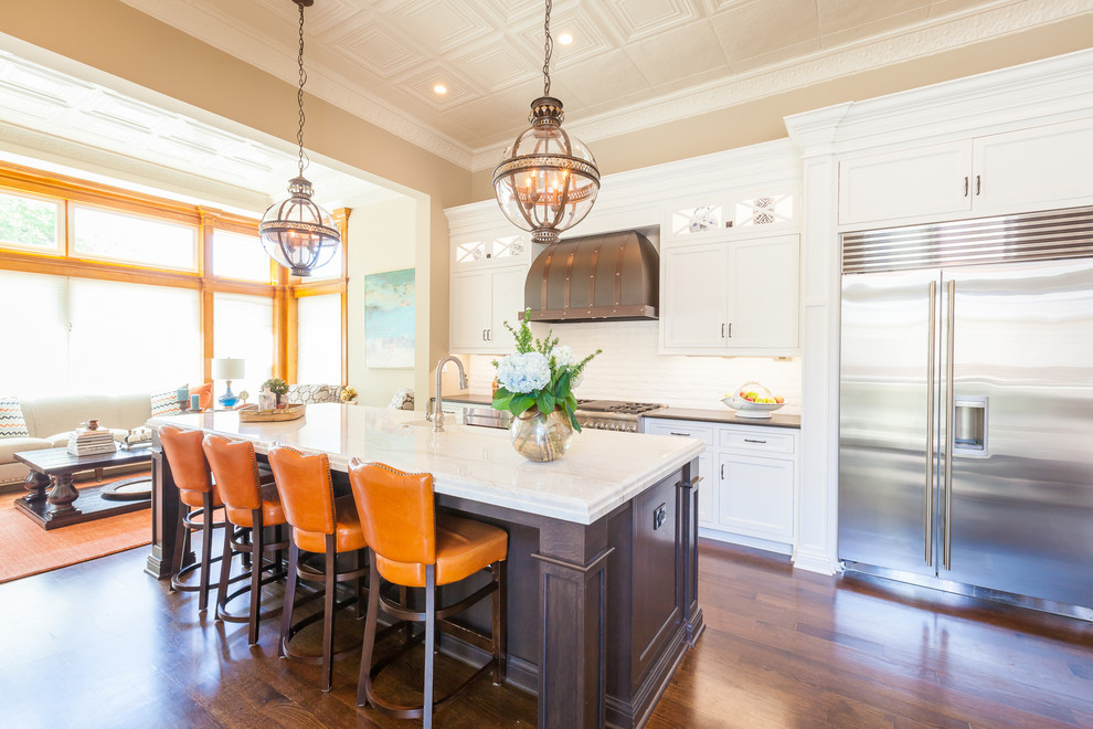 Eat-in kitchen - large traditional u-shaped dark wood floor and brown floor eat-in kitchen idea in Chicago with a farmhouse sink, beaded inset cabinets, white cabinets, quartzite countertops, white backsplash, brick backsplash, stainless steel appliances and an island