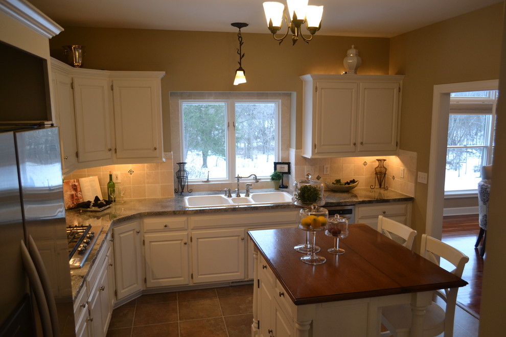 Exempel på ett avskilt, mellanstort klassiskt l-kök, med en trippel diskho, luckor med upphöjd panel, vita skåp, träbänkskiva, beige stänkskydd, stänkskydd i keramik, rostfria vitvaror, klinkergolv i keramik, en köksö och beiget golv