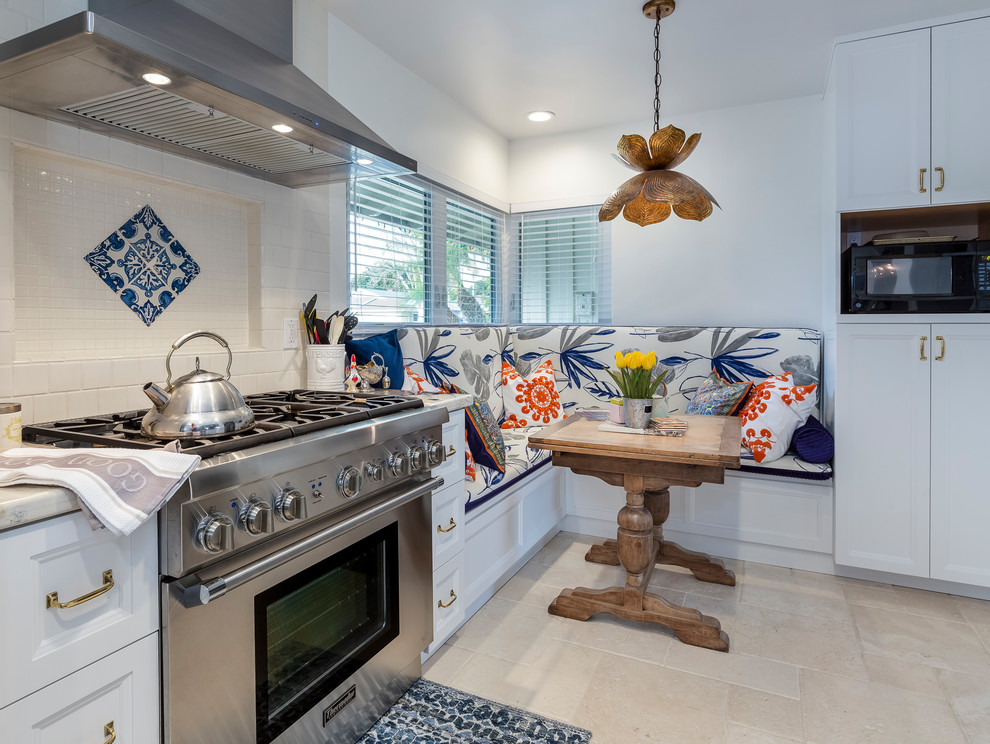 Bild på ett mellanstort vintage kök, med en rustik diskho, vita skåp, granitbänkskiva, rostfria vitvaror, vitt stänkskydd, stänkskydd i keramik, travertin golv och luckor med infälld panel