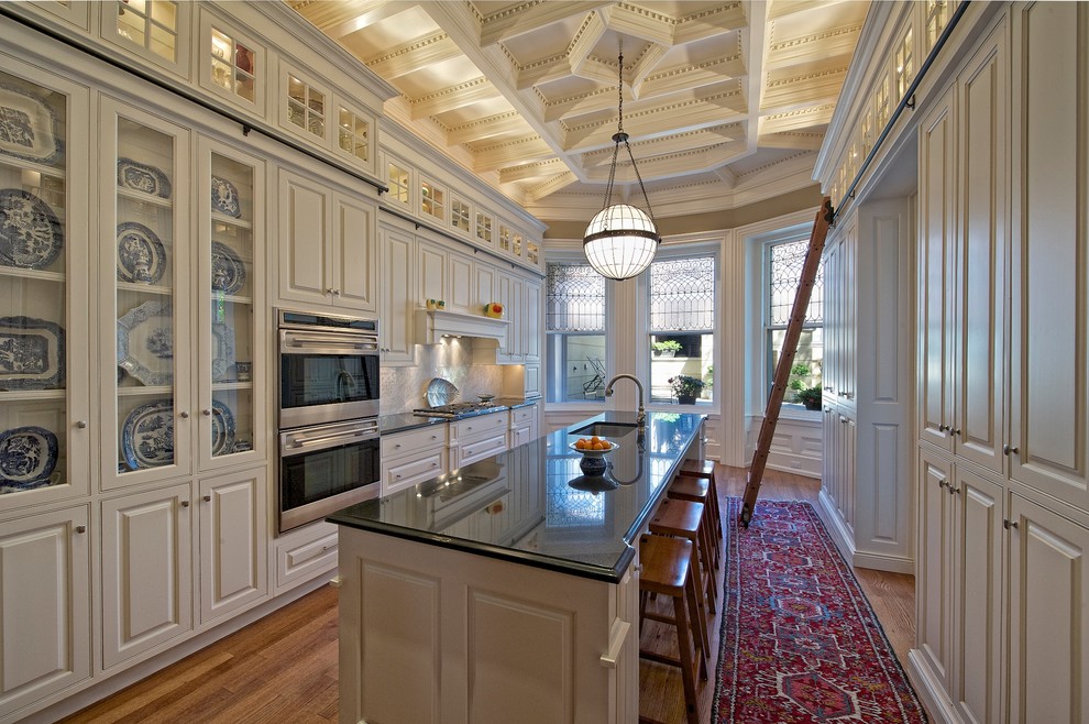 Imagen de cocina clásica cerrada con armarios con rebordes decorativos, electrodomésticos de acero inoxidable, puertas de armario beige y barras de cocina