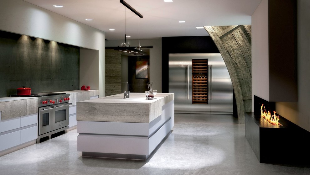 Example of a mid-sized minimalist galley concrete floor and gray floor enclosed kitchen design in Boston with an undermount sink, flat-panel cabinets, white cabinets, wood countertops, gray backsplash, stone slab backsplash, stainless steel appliances and an island