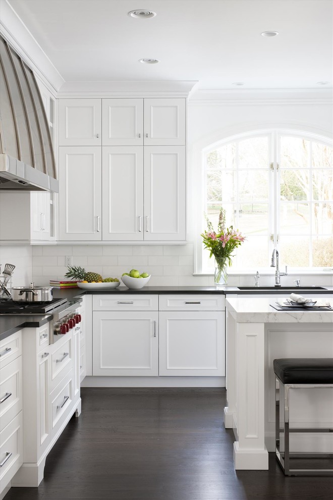 Immagine di una cucina ad U tradizionale con ante bianche, paraspruzzi bianco, parquet scuro e pavimento marrone