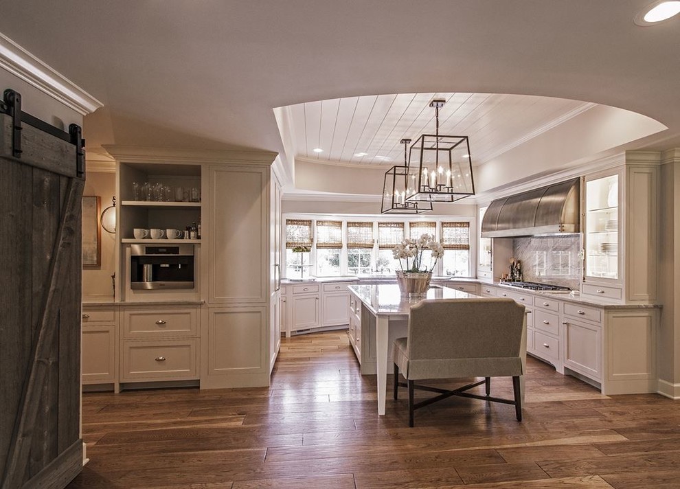 Enclosed kitchen - large transitional l-shaped light wood floor and brown floor enclosed kitchen idea in Austin with a farmhouse sink, recessed-panel cabinets, white cabinets, quartzite countertops, gray backsplash, stone slab backsplash, stainless steel appliances and an island
