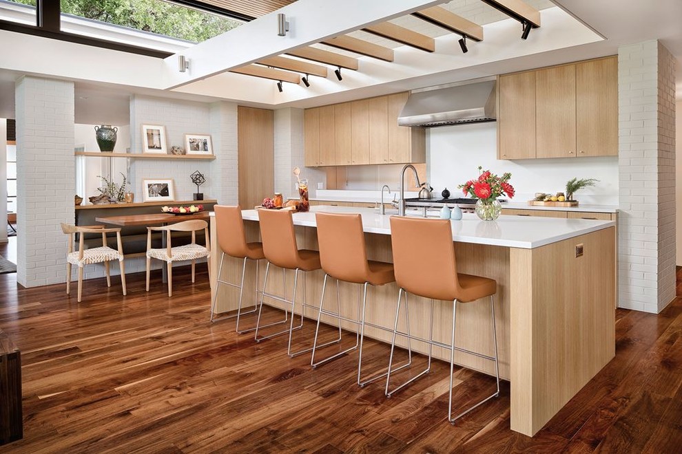 Foto på ett mellanstort funkis linjärt kök med öppen planlösning, med en undermonterad diskho, släta luckor, skåp i ljust trä, bänkskiva i koppar, rostfria vitvaror, mellanmörkt trägolv, en köksö och brunt golv