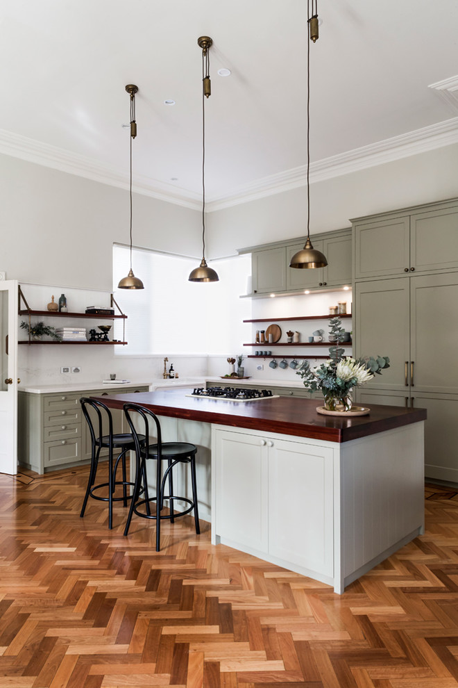 Example of a transitional l-shaped medium tone wood floor and brown floor kitchen design in Perth with shaker cabinets, gray cabinets, white backsplash and an island
