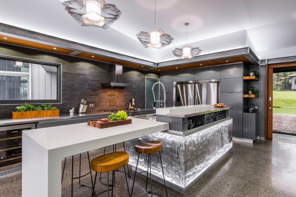 Contemporary l-shaped kitchen in Brisbane with a double-bowl sink, flat-panel cabinets, grey cabinets, stainless steel worktops, grey splashback, ceramic splashback, stainless steel appliances, concrete flooring and an island.