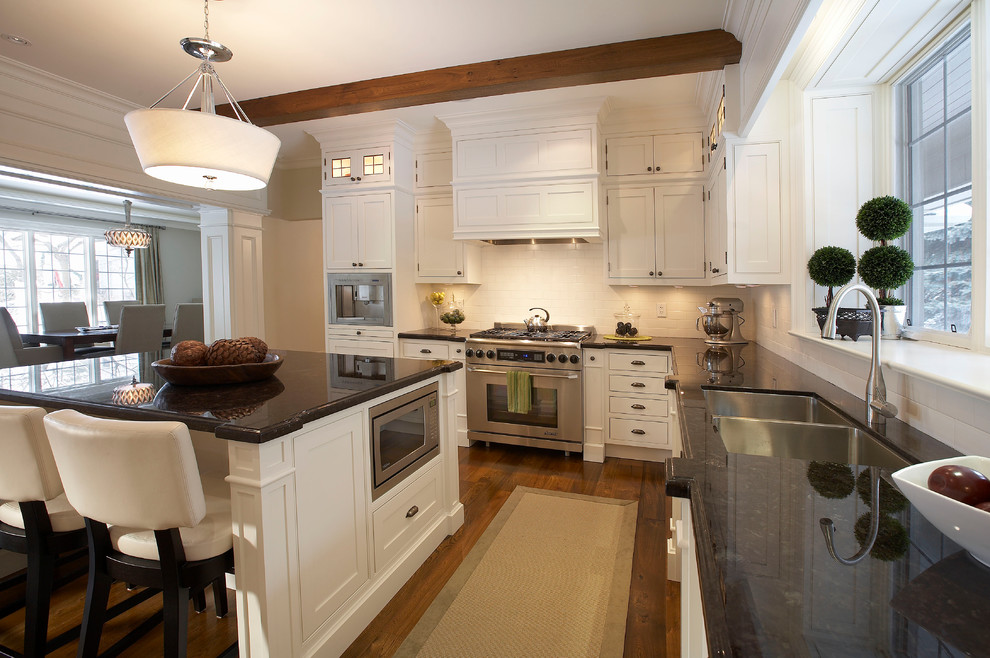 Example of a large classic u-shaped medium tone wood floor eat-in kitchen design in Toronto with a double-bowl sink, shaker cabinets, white cabinets, granite countertops, white backsplash, subway tile backsplash, stainless steel appliances and an island