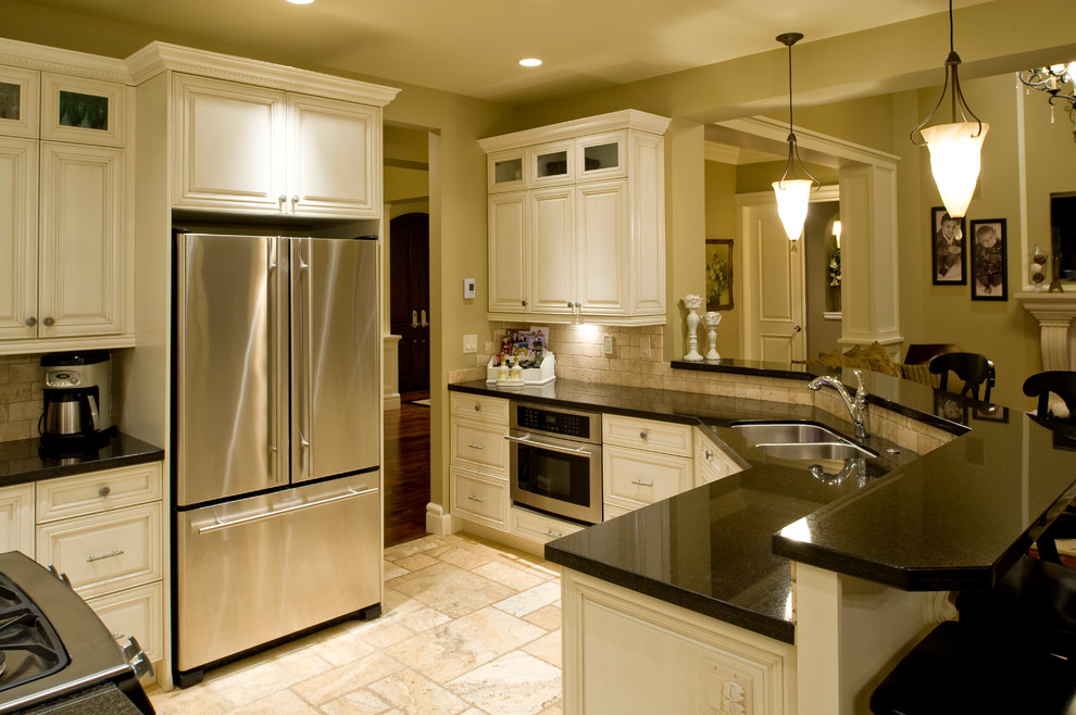 Bild på ett stort amerikanskt kök, med en undermonterad diskho, luckor med upphöjd panel, vita skåp, granitbänkskiva, flerfärgad stänkskydd, stänkskydd i stenkakel, rostfria vitvaror, travertin golv och en köksö
