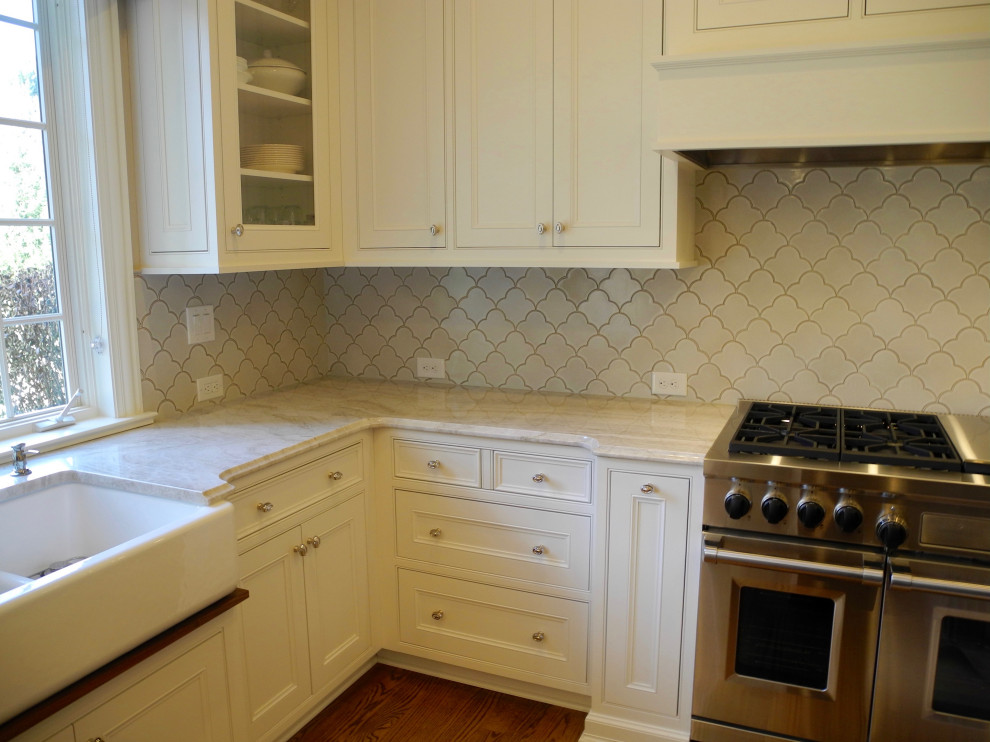 Cette image montre une cuisine traditionnelle avec plan de travail en marbre, une crédence blanche, une crédence en céramique, un sol en bois brun et un plan de travail blanc.