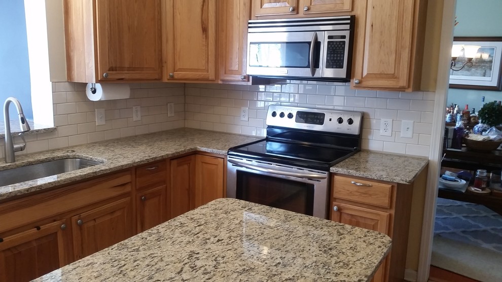 Enclosed kitchen - mid-sized traditional l-shaped enclosed kitchen idea in Baltimore with an undermount sink, raised-panel cabinets, medium tone wood cabinets, granite countertops, white backsplash, subway tile backsplash, stainless steel appliances and an island