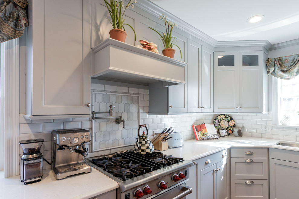 Foto på ett mellanstort vintage vit kök, med en undermonterad diskho, luckor med infälld panel, grå skåp, bänkskiva i kvarts, vitt stänkskydd, stänkskydd i tunnelbanekakel, rostfria vitvaror, mellanmörkt trägolv, en köksö och brunt golv