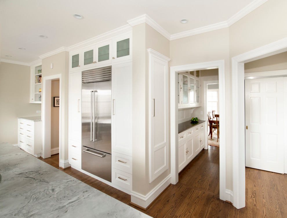 Example of a mid-sized transitional l-shaped dark wood floor eat-in kitchen design in Chicago with an undermount sink, recessed-panel cabinets, white cabinets, quartzite countertops, white backsplash, glass tile backsplash, stainless steel appliances and an island