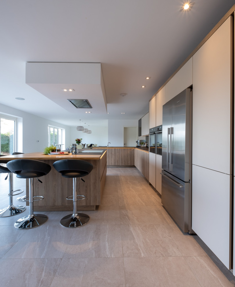 Modern inredning av ett stort grå grått kök, med släta luckor, vita skåp, grått stänkskydd, glaspanel som stänkskydd, klinkergolv i porslin, en köksö och flerfärgat golv