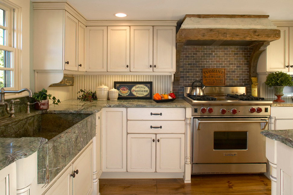 Inredning av ett lantligt mellanstort kök, med en rustik diskho, luckor med infälld panel, vita skåp, granitbänkskiva, vitt stänkskydd, stänkskydd i trä, rostfria vitvaror och mellanmörkt trägolv