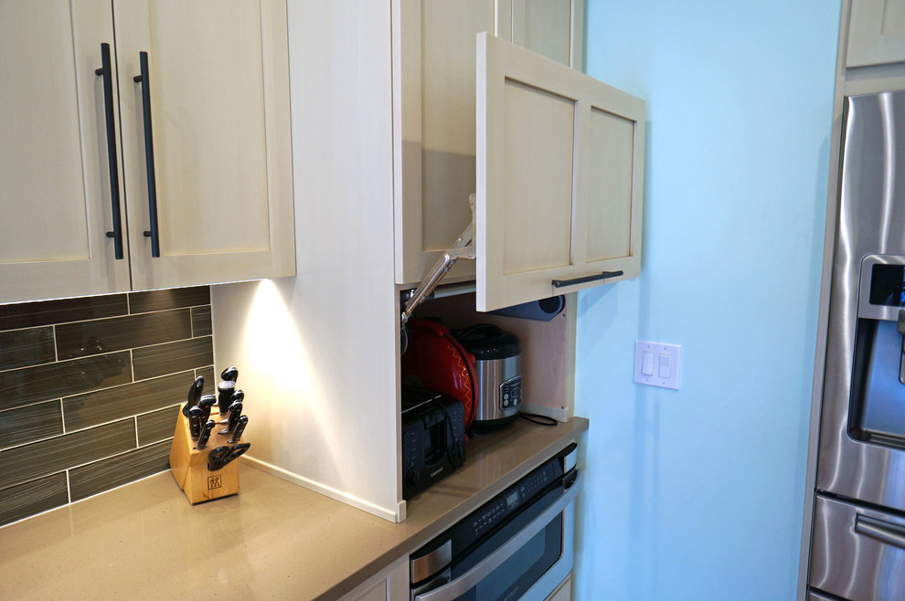 Exempel på ett mellanstort eklektiskt kök, med en rustik diskho, skåp i shakerstil, beige skåp, bänkskiva i kvarts, stänkskydd med metallisk yta, stänkskydd i glaskakel, rostfria vitvaror, mellanmörkt trägolv och en köksö