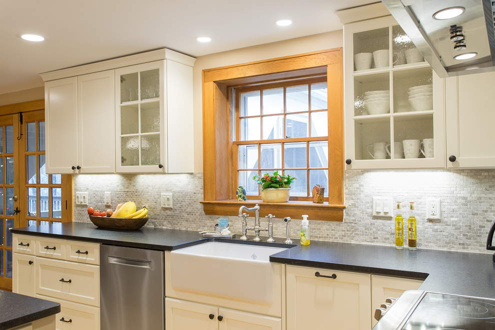 Klassisk inredning av ett kök, med en rustik diskho, luckor med infälld panel, vita skåp, bänkskiva i koppar, vitt stänkskydd, rostfria vitvaror och mellanmörkt trägolv