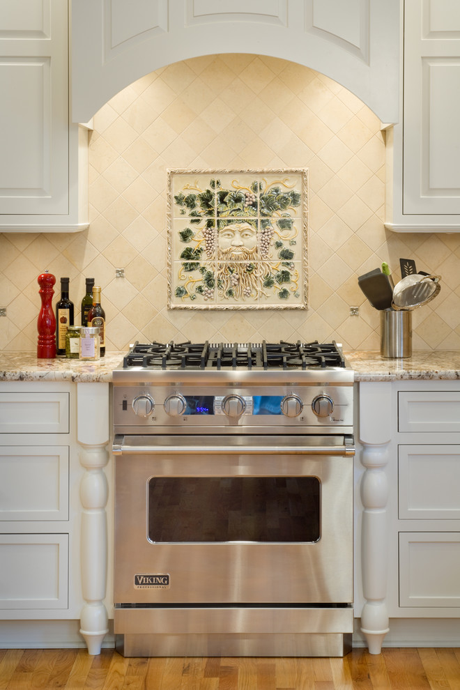 Cette image montre une cuisine traditionnelle avec des portes de placard blanches, une crédence beige et un électroménager en acier inoxydable.