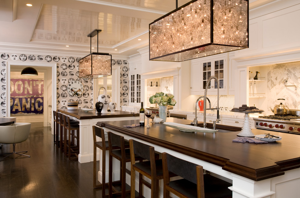 Example of a trendy eat-in kitchen design in New York with glass-front cabinets, white cabinets, wood countertops and white backsplash