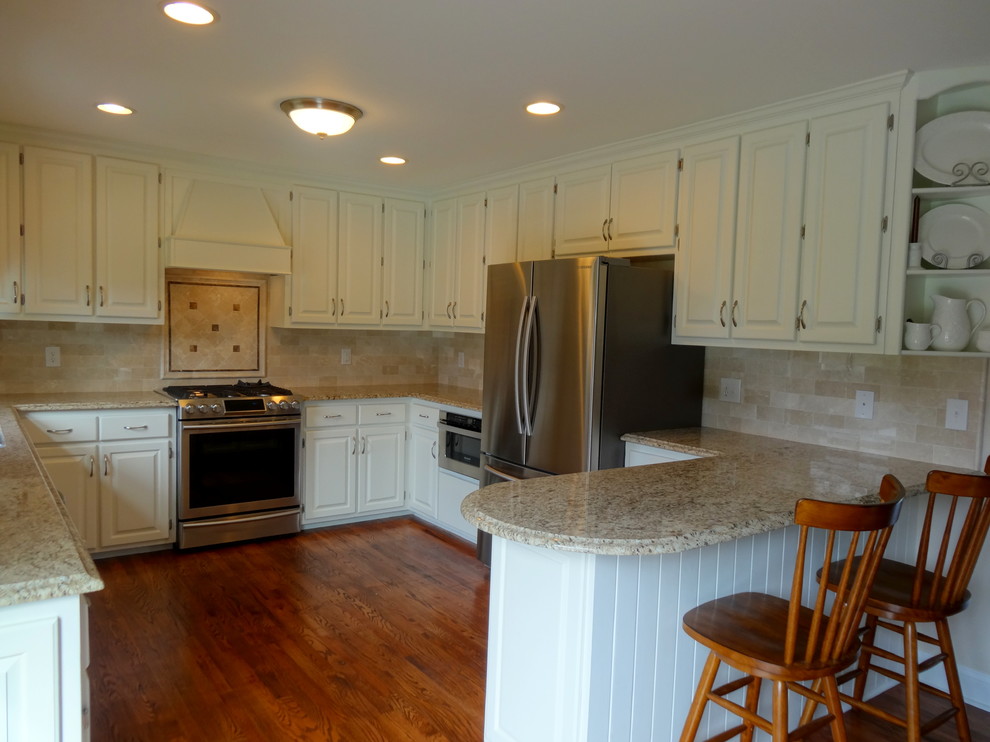 Exempel på ett mellanstort klassiskt kök, med en dubbel diskho, luckor med upphöjd panel, vita skåp, granitbänkskiva, beige stänkskydd, stänkskydd i keramik, rostfria vitvaror, mörkt trägolv och en halv köksö