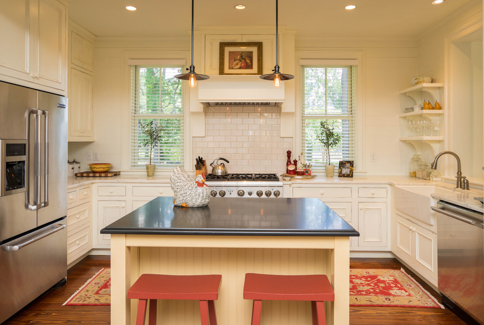 This is an example of a farmhouse u-shaped kitchen in Charleston with a belfast sink, recessed-panel cabinets, white cabinets, white splashback, metro tiled splashback, stainless steel appliances, dark hardwood flooring and multiple islands.