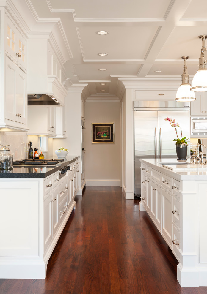 Mid-sized elegant l-shaped medium tone wood floor open concept kitchen photo in Salt Lake City with an undermount sink, shaker cabinets, white cabinets, marble countertops, white backsplash, stone slab backsplash, stainless steel appliances and an island