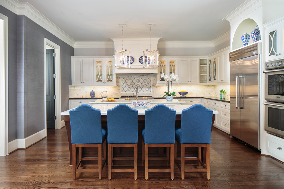 Klassische Küche in L-Form mit Glasfronten, weißen Schränken, bunter Rückwand, Küchengeräten aus Edelstahl, braunem Holzboden und Kücheninsel in Houston