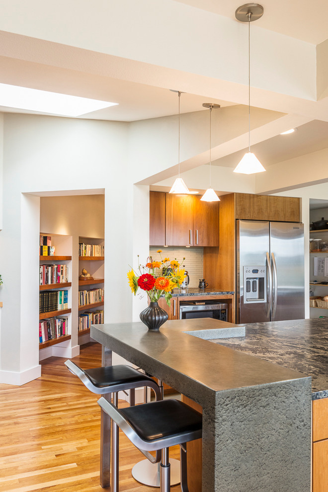 Große Moderne Küche mit flächenbündigen Schrankfronten, hellbraunen Holzschränken, Granit-Arbeitsplatte, Küchengeräten aus Edelstahl und Kücheninsel in Denver