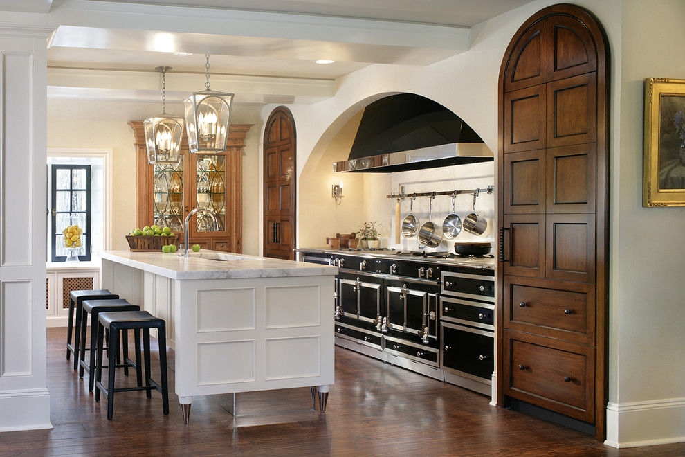 Immagine di una cucina parallela tradizionale con ante in legno bruno, top in marmo e elettrodomestici neri