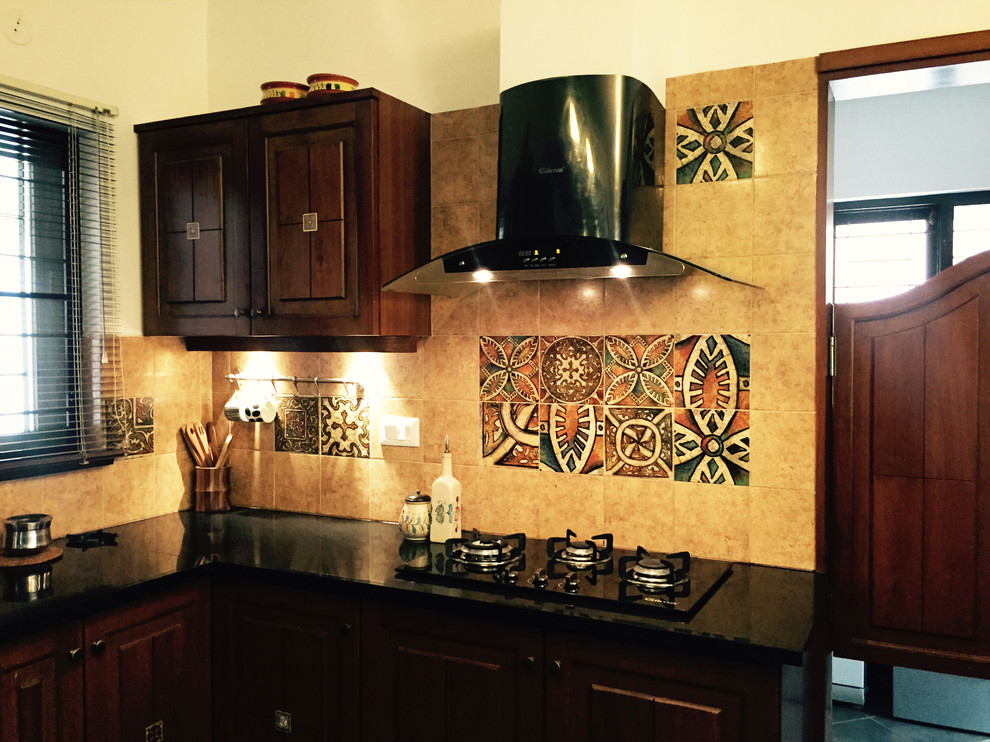 Kleine Urige Küche in L-Form mit profilierten Schrankfronten, dunklen Holzschränken, Granit-Arbeitsplatte, Küchenrückwand in Beige und Kalkstein in Bangalore