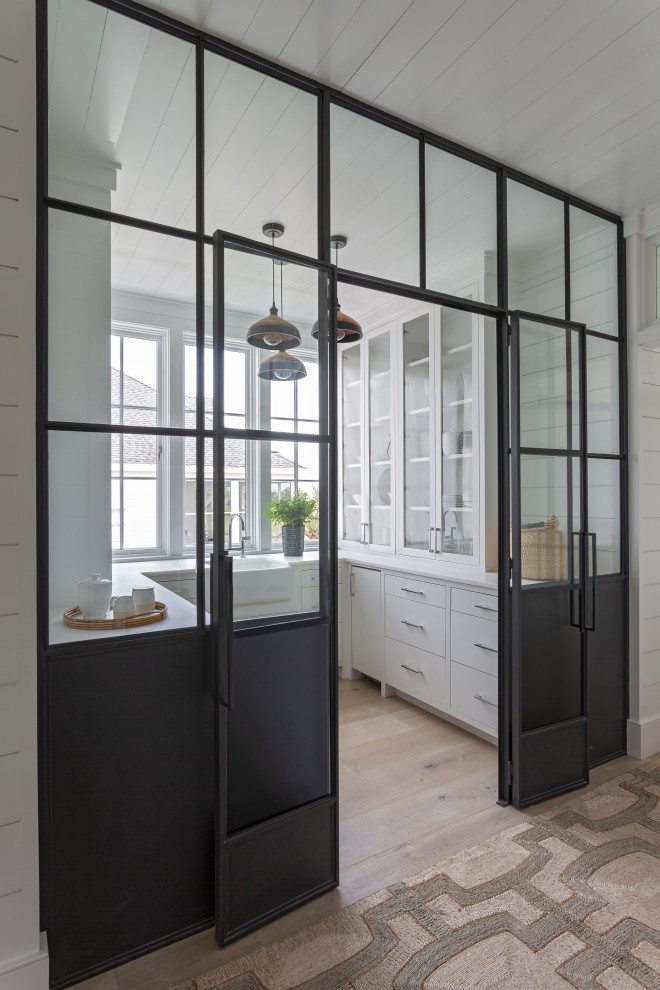 Kitchen pantry - mid-sized coastal u-shaped light wood floor and beige floor kitchen pantry idea in Charleston with a farmhouse sink, flat-panel cabinets, white cabinets, no island and white countertops