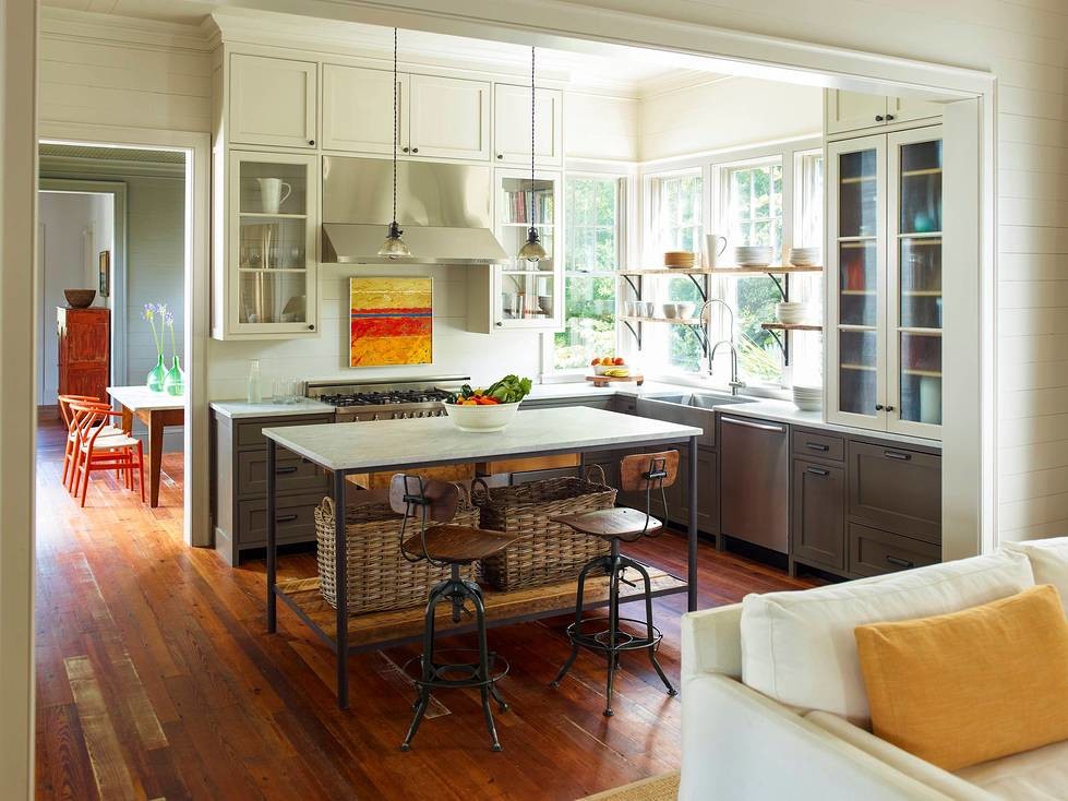 Example of a mid-sized beach style l-shaped medium tone wood floor kitchen design in Charleston with a farmhouse sink, glass-front cabinets, gray cabinets, marble countertops, white backsplash, window backsplash, stainless steel appliances and an island