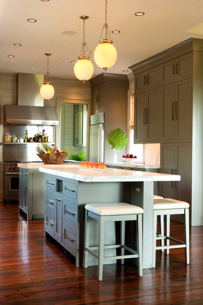 チャールストンにあるトロピカルスタイルのおしゃれなマルチアイランドキッチン (シェーカースタイル扉のキャビネット、緑のキャビネット、メタリックのキッチンパネル、無垢フローリング、茶色い床、白いキッチンカウンター) の写真