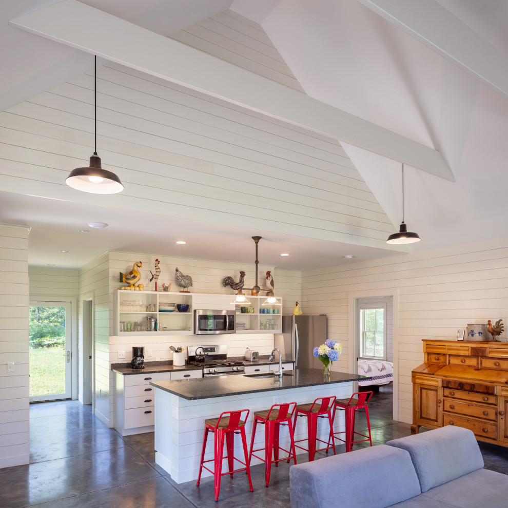 Inspiration för ett mellanstort lantligt grå linjärt grått kök med öppen planlösning, med en undermonterad diskho, släta luckor, vita skåp, granitbänkskiva, vitt stänkskydd, stänkskydd i trä, rostfria vitvaror, betonggolv, en köksö och grått golv
