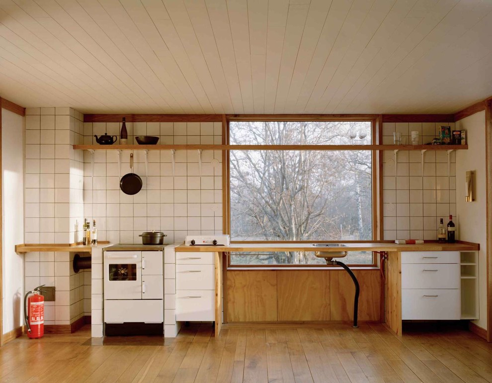 Источник вдохновения для домашнего уюта: большая кухня в скандинавском стиле с одинарной мойкой, плоскими фасадами, белыми фасадами, деревянной столешницей, белой техникой и паркетным полом среднего тона без острова