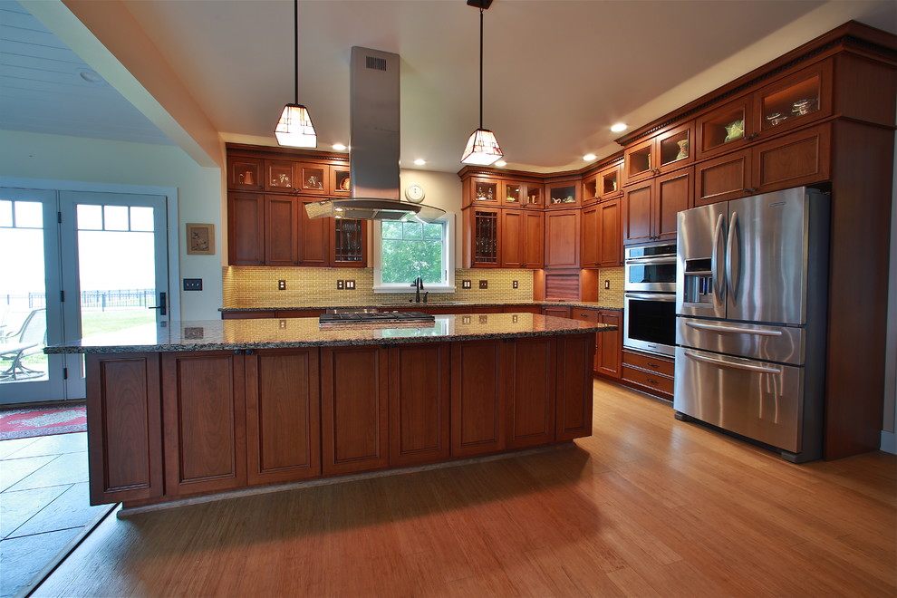 Inspiration for a large craftsman l-shaped bamboo floor eat-in kitchen remodel in Burlington with flat-panel cabinets, medium tone wood cabinets, quartz countertops, green backsplash, glass tile backsplash, stainless steel appliances and an island