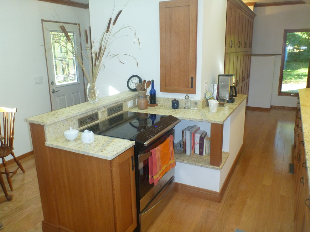 Example of a small classic galley light wood floor enclosed kitchen design in Boston with an undermount sink, recessed-panel cabinets, medium tone wood cabinets, granite countertops, beige backsplash, subway tile backsplash and stainless steel appliances