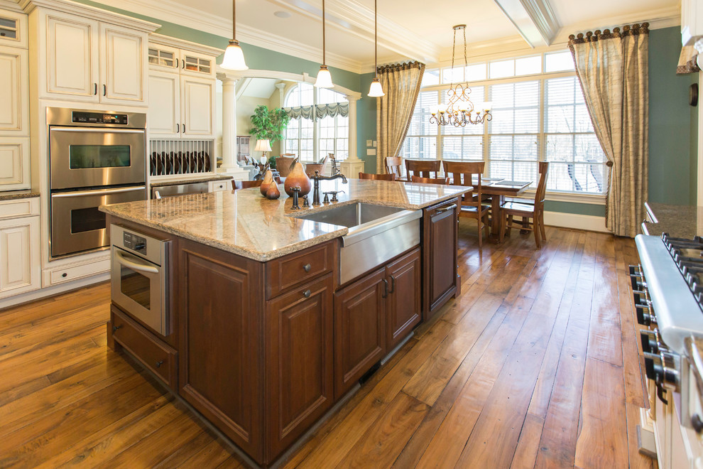Eat-in kitchen - mid-sized transitional u-shaped medium tone wood floor eat-in kitchen idea in Raleigh with a farmhouse sink, raised-panel cabinets, white cabinets, granite countertops, white backsplash, stone tile backsplash, white appliances and an island