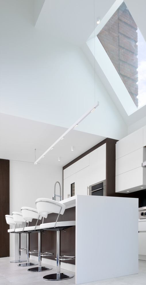 Inredning av ett modernt kök, med en undermonterad diskho, vita skåp, fönster som stänkskydd, integrerade vitvaror, en köksö och vitt golv