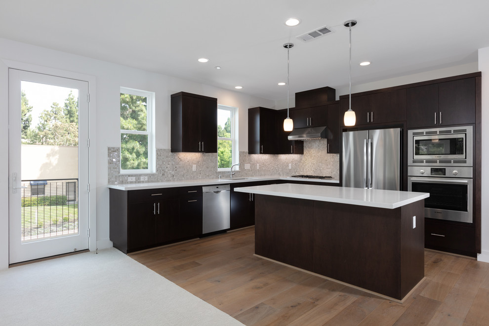 L-shaped open concept kitchen photo in San Francisco with an undermount sink, flat-panel cabinets, dark wood cabinets, stainless steel appliances and an island