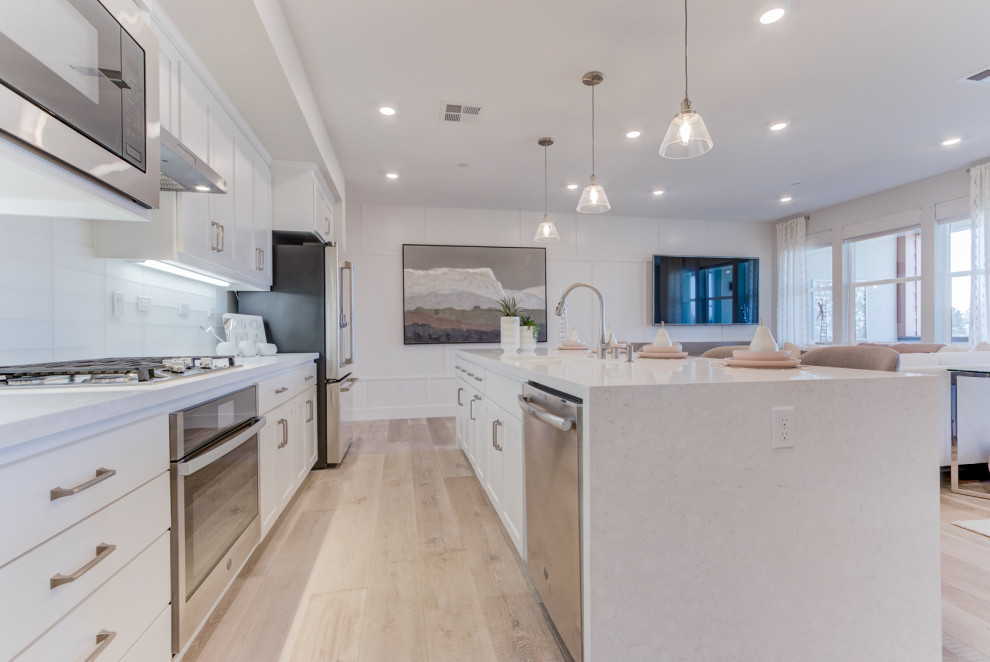 L-shaped open concept kitchen photo in San Francisco with an undermount sink, recessed-panel cabinets, stainless steel appliances and an island