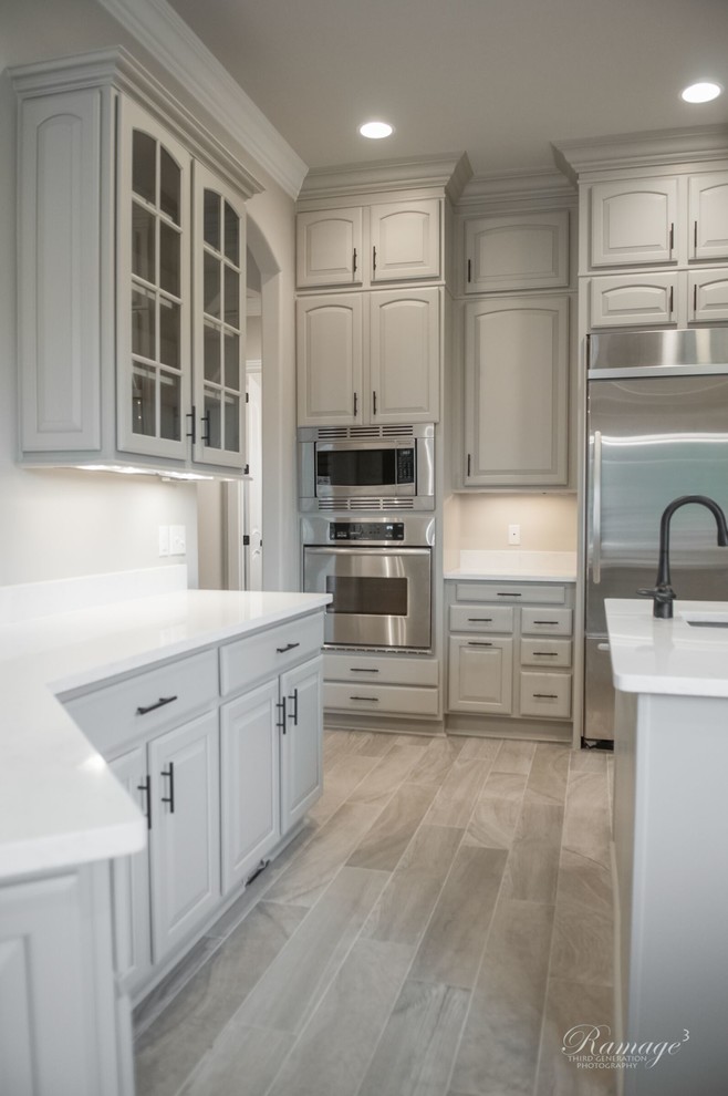 Bild på ett mellanstort vintage vit vitt kök, med en undermonterad diskho, luckor med upphöjd panel, grå skåp, beige stänkskydd, stänkskydd i keramik, rostfria vitvaror, klinkergolv i porslin, en köksö och grått golv