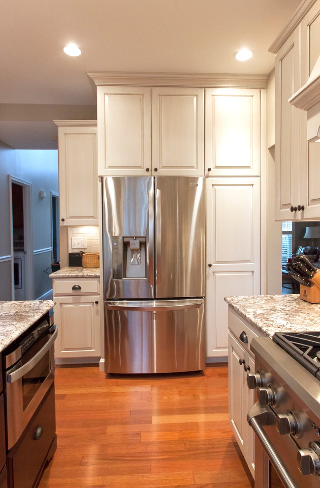 Example of a classic kitchen design in DC Metro with raised-panel cabinets, white cabinets, granite countertops, white backsplash and stainless steel appliances