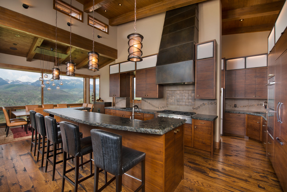 Cette image montre une grande cuisine ouverte craftsman en L et bois brun avec un placard à porte plane, un plan de travail en granite, une crédence marron, une crédence en dalle métallique et îlot.