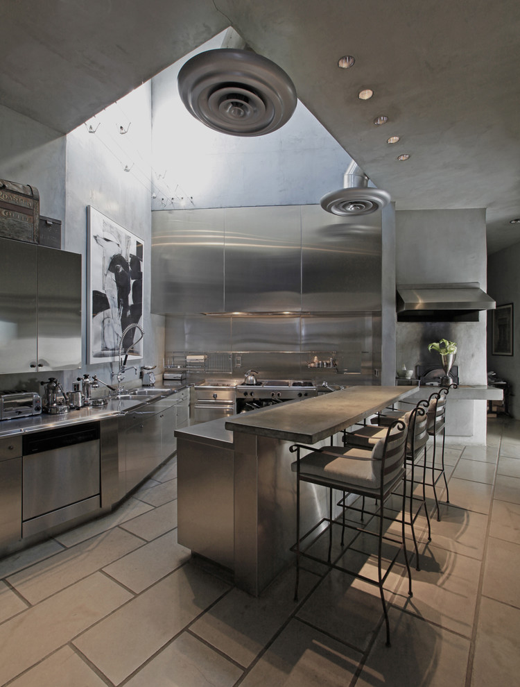 Bild på ett industriellt kök, med rostfria vitvaror, skåp i rostfritt stål, bänkskiva i rostfritt stål, släta luckor, stänkskydd med metallisk yta och stänkskydd i metallkakel