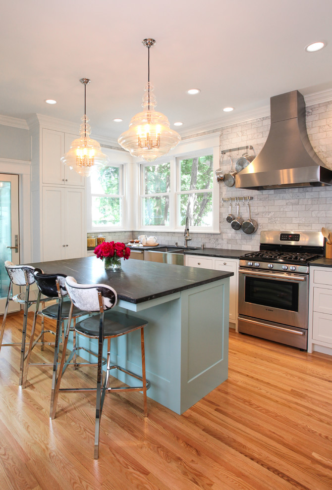 Mid-sized eclectic u-shaped medium tone wood floor enclosed kitchen photo in Minneapolis with a double-bowl sink, flat-panel cabinets, white cabinets, soapstone countertops, gray backsplash, marble backsplash, stainless steel appliances and an island