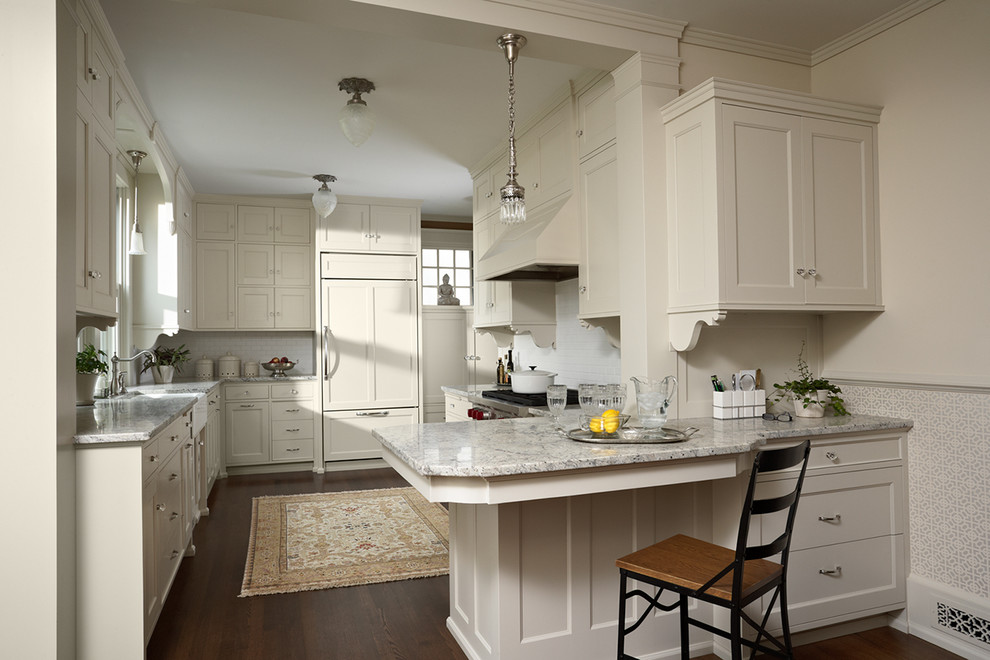 Bild på ett mellanstort vintage kök, med en rustik diskho, luckor med infälld panel, vita skåp, granitbänkskiva, vitt stänkskydd, stänkskydd i keramik, integrerade vitvaror, mörkt trägolv, en halv köksö och brunt golv