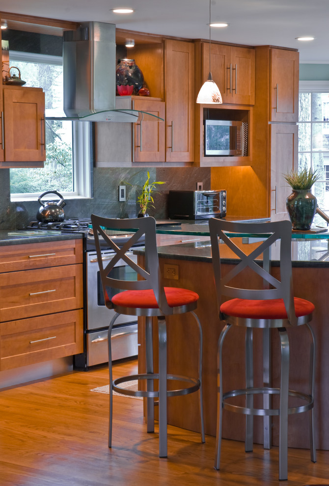 Inredning av ett modernt mellanstort linjärt kök och matrum, med en nedsänkt diskho, luckor med upphöjd panel, skåp i mellenmörkt trä, granitbänkskiva, svart stänkskydd, stänkskydd i sten, rostfria vitvaror, mellanmörkt trägolv och en köksö