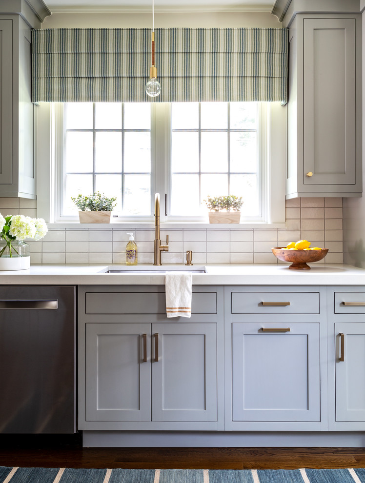 Bild på ett vintage vit vitt kök, med en undermonterad diskho, skåp i shakerstil, grå skåp, bänkskiva i kvarts, vitt stänkskydd, stänkskydd i keramik, rostfria vitvaror, mörkt trägolv och brunt golv