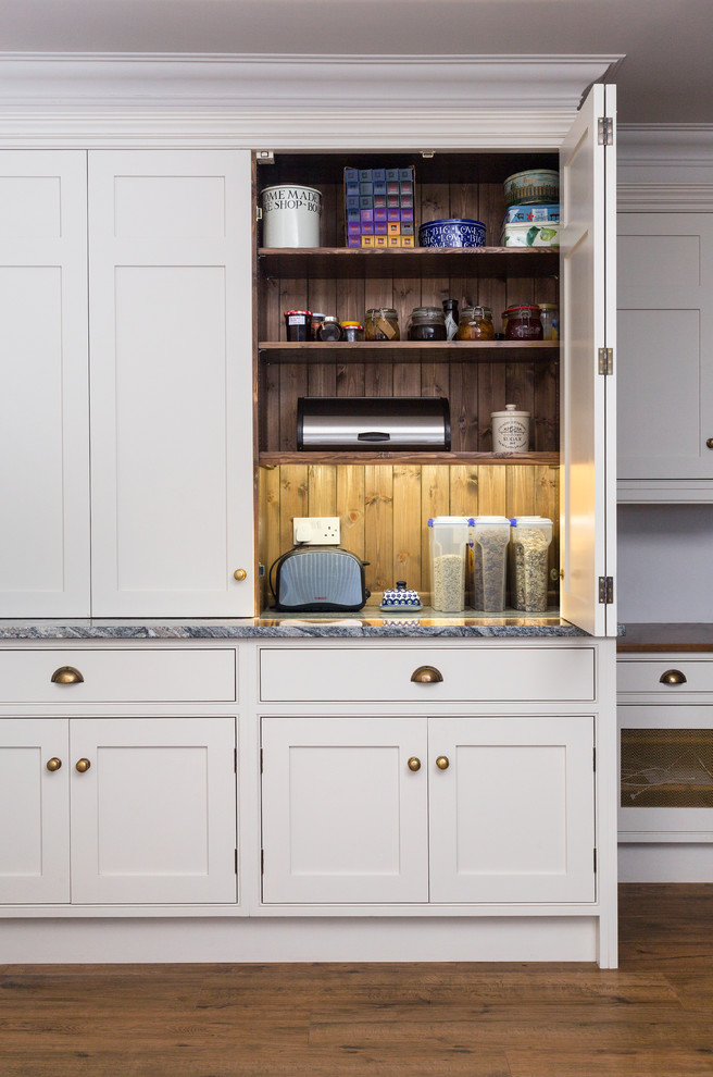 Offene Klassische Küche mit Landhausspüle, Kassettenfronten, blauen Schränken, Granit-Arbeitsplatte, Küchenrückwand in Schwarz, Glasrückwand und Kücheninsel in Kent